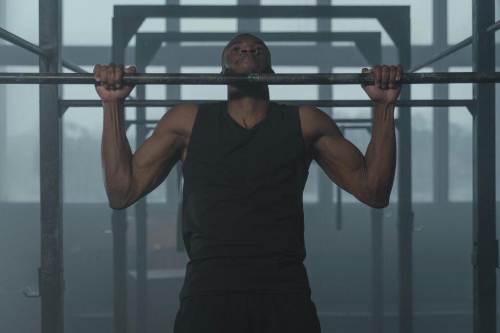 A Man in Black Tank Top Holding on Metal Bars